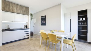Una cocina moderna con armarios blancos, una mesa de comedor con sillas amarillas y un póster blanco y negro en la pared.