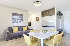 Ein modernes Wohnzimmer mit einer Couch, einem Esstisch, Stühlen und Kunstwerken an der Wand.