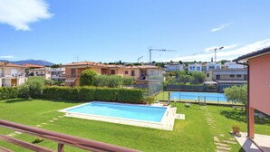 Zona residencial con piscina, cancha de tenis y vista a una montaña al fondo.