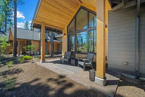 A modern building with a covered patio area featuring outdoor seating and a view of the surrounding landscape. - NL33B | 56457-2 Elk Run Drive (Sunriver)