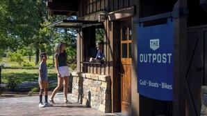 A building with a sign reading 'The Outpost' and a list of amenities including golf, boats, and bikes. - NL33A | 56457-1 Elk Run Drive (Sunriver)