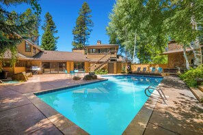 Ein Swimmingpool mit einer Steindeck und Sitzgelegenheiten im Freien sowie einer Holzterrasse.