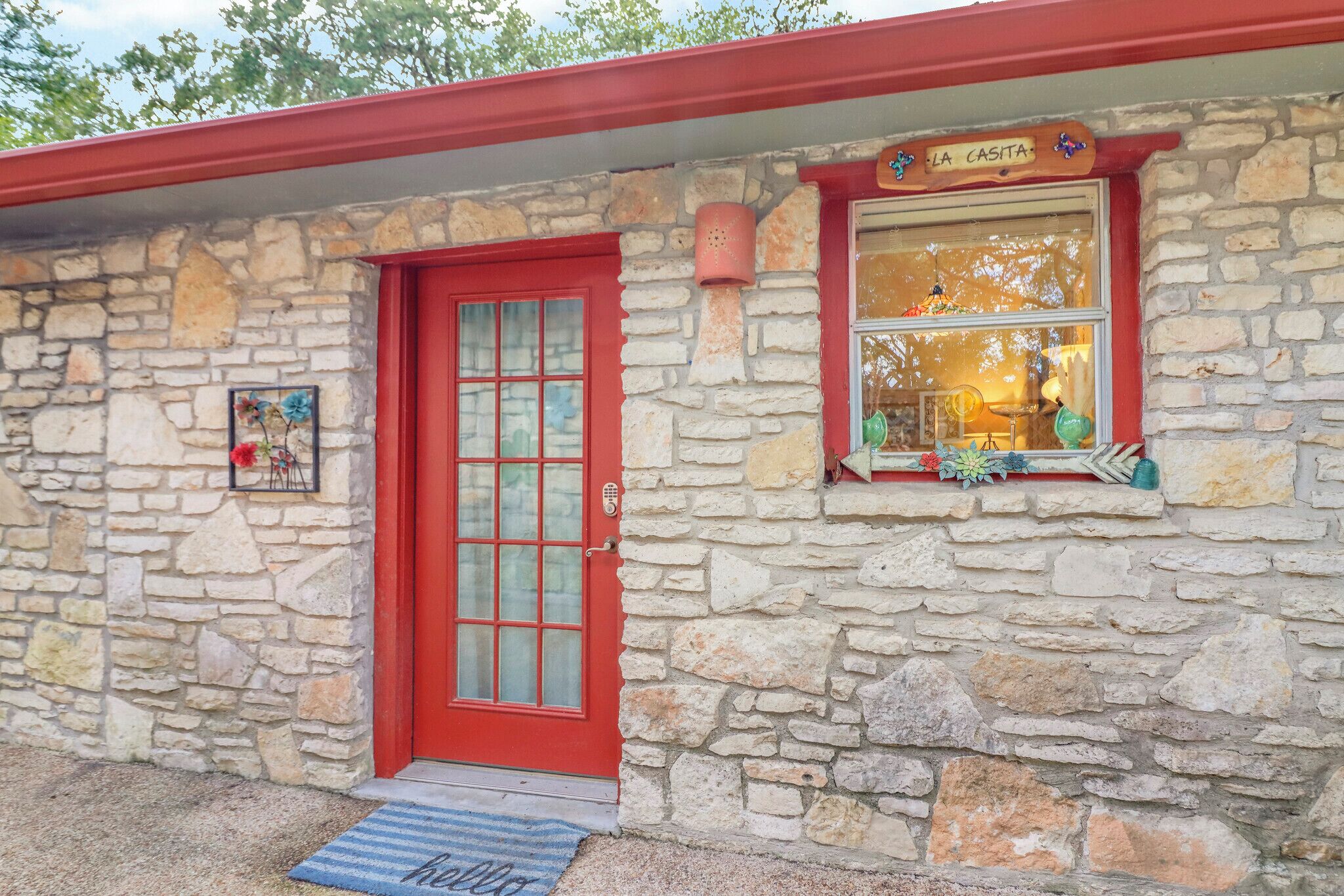 Ein Steinhaus mit einer roten Tür und einem Fenster, das ein Schild mit der Aufschrift 'LA CASITA' zeigt.