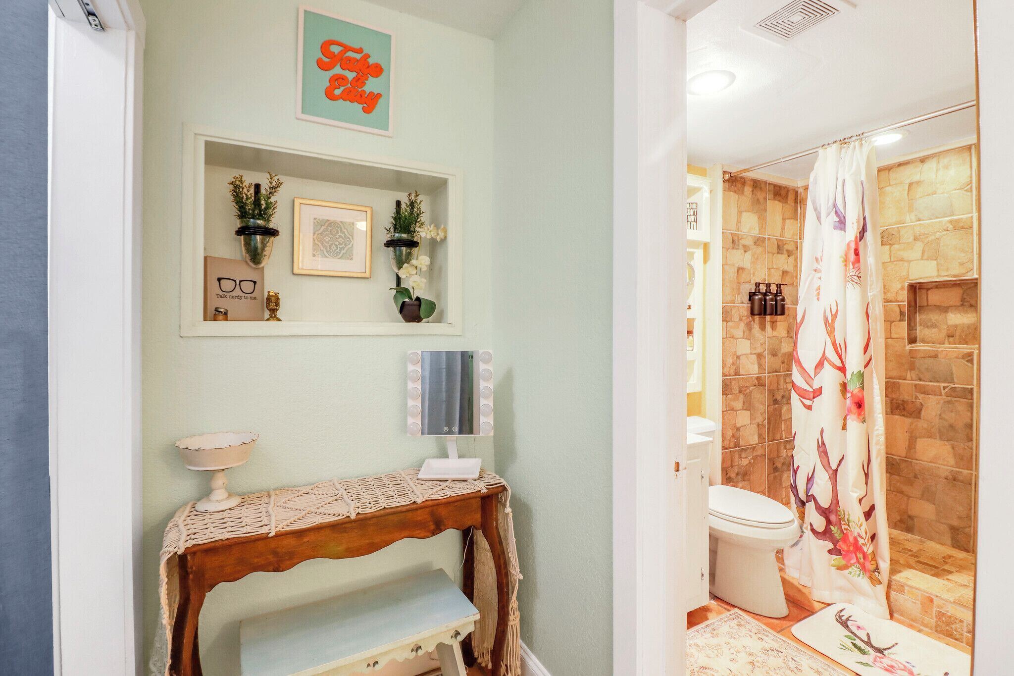 Une salle de bain avec un rideau de douche, des toilettes et un meuble-lavabo avec un miroir.