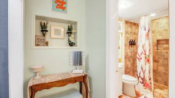 Une salle de bain avec un rideau de douche, des toilettes et un meuble-lavabo avec un miroir.