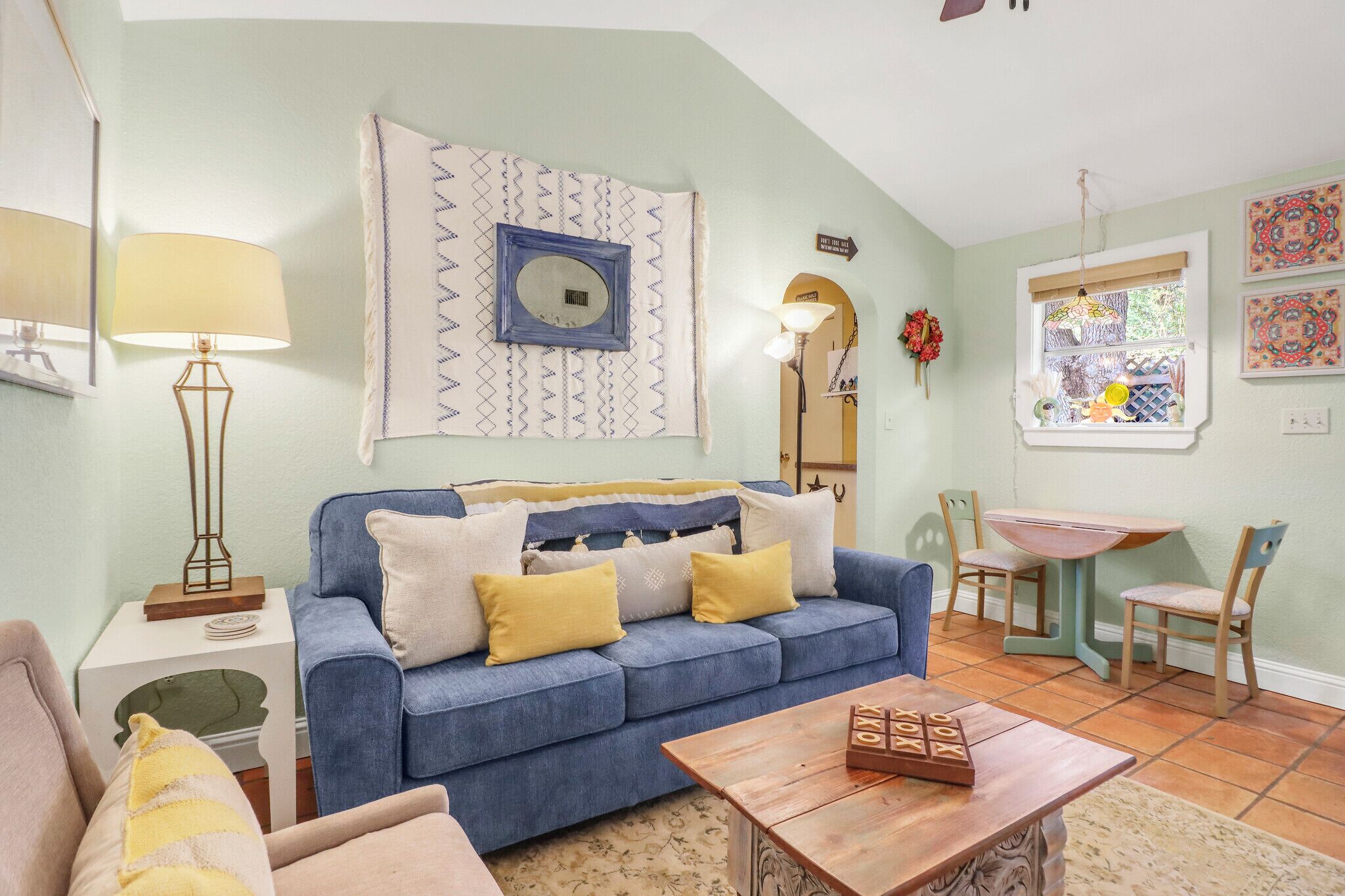 A living room with a blue sofa, a wooden coffee table, and a dining area with a small table and chairs.