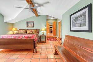 A bedroom with a bed, bedside lamps, a ceiling fan, a framed picture, and a wooden bench. - Hillsedge Haciendas | Multi unit Hill Country Retreat with Hot Tubs (Wimberley)