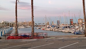 A marina with boats docked, palm trees, and buildings in the background. - Air-conditioned apartment with a pool and a large terrace on the waterfront (Le Barcarès)