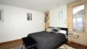 A modern bedroom with a bed, a bench, a wall-mounted mirror, and a window. - Air-conditioned apartment with a pool and a large terrace on the waterfront (Le Barcarès)