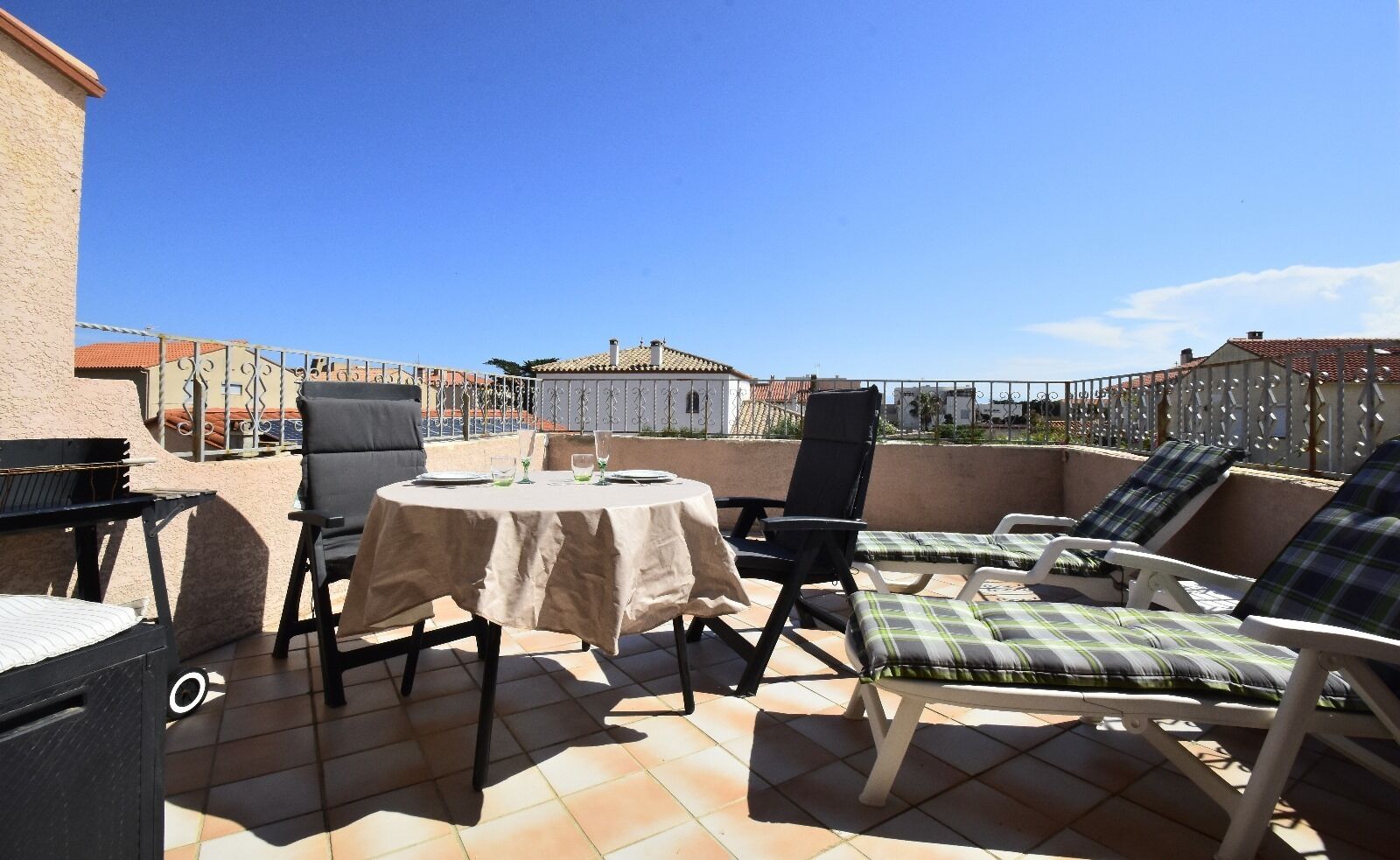 A rooftop terrace with a round table, chairs, and lounge seating.