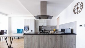 Una cucina moderna con isola centrale, elettrodomestici integrati e zona pranzo con una sedia blu.