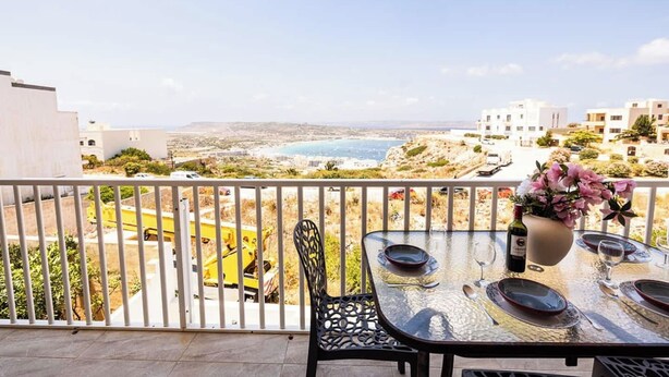 Un balcone con un tavolo apparecchiato per due, con vista sulla città costiera.