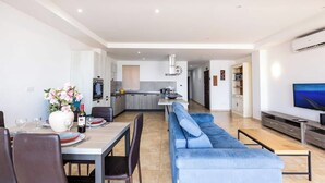 Un'area living moderna con un tavolo da pranzo, un divano blu e una TV.