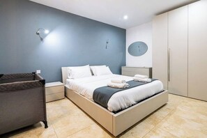 Ein modernes Schlafzimmer mit Bett, Nachttischen, einem Kleiderschrank und einer Wandleuchte.