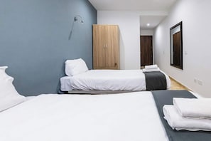 Ein Hotelzimmer mit zwei Betten, einem Kleiderschrank, einer Dusche und einem Spiegel.