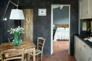 A rustic kitchen with a wooden table, a vase of flowers, and a hanging light fixture. - Apartment in farmstead with olive groves and pool (Buggiano)