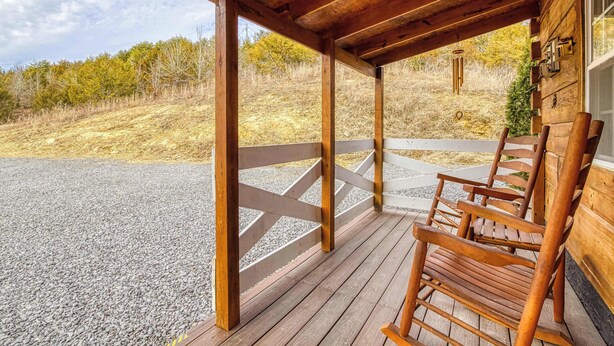 Eine hölzerne Veranda mit einem Schotterweg, Holzgeländern und Blick auf eine natürliche Landschaft.