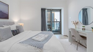 Ein modernes Hotelzimmer mit einem großen Bett, einem Schreibtisch, einem Sessel, einem runden Spiegel und Blick auf die Stadt durch das Fenster.