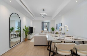 A modern living room with a sofa, a dining table set for two, and a large mirror on the wall.