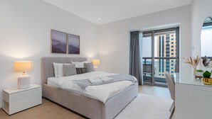 Ein modernes Schlafzimmer mit einem Bett, Nachttischen, einem großen Fenster und Blick auf Gebäude.