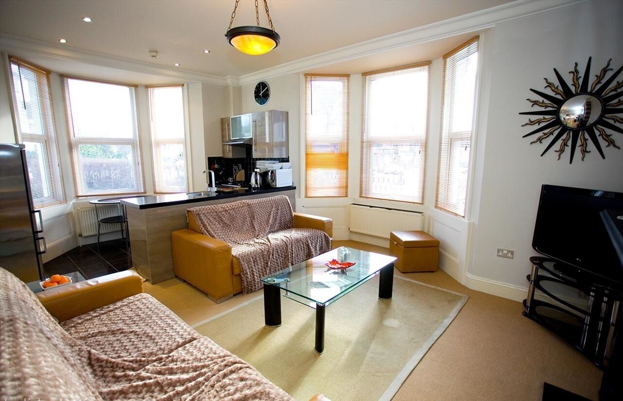 A living room with a sofa, a glass coffee table, and a television.