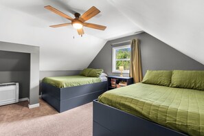 Ein Schlafzimmer mit zwei Betten, einem Deckenventilator, einem Fenster mit Vorhängen und einer Heizung.