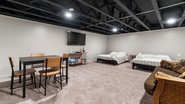 Una habitación con una mesa, sillas, una cama, un sofá y un televisor montado en la pared.