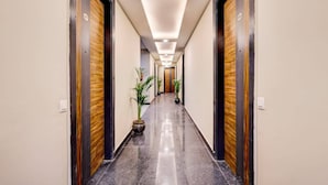 Un corridoio d'albergo con pavimento lucido, porte in legno e illuminazione a incasso.