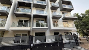 A multi-story residential building with balconies, a gated entrance, and a clear sky.
