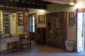 Una habitación con muebles de madera, un jarrón grande y un aparador con puertas de cristal.