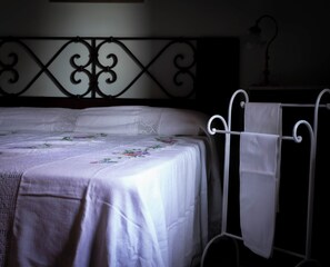Una cama con una colcha blanca y cabecera de metal.