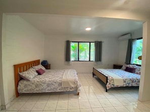 Una habitación con dos camas, una ventana con cortinas y un equipo de aire acondicionado.