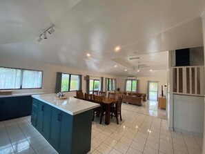 Una cocina amplia con una isla central, comedor con sillas y sala de estar con sofá.