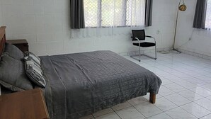 A room with a bed, a chair, a window with curtains, and an air conditioning unit. - Home in Siusega - Vonnys Garden House (Vaitele)
