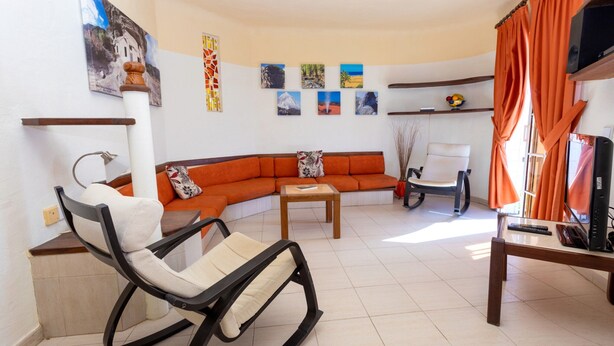 A living room with a sofa, a rocking chair, a coffee table, and a TV. - Apartment in Bahia Feliz by Playa del Aguila (San Bartolomé de Tirajana)