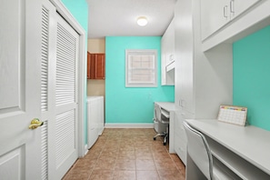 A laundry room with a white washing machine, a dryer, a calendar, and a window with blinds. - Havens 1136 Back on Program! Beautiful & Spacious! In Barefoot Resort! (North Myrtle Beach)