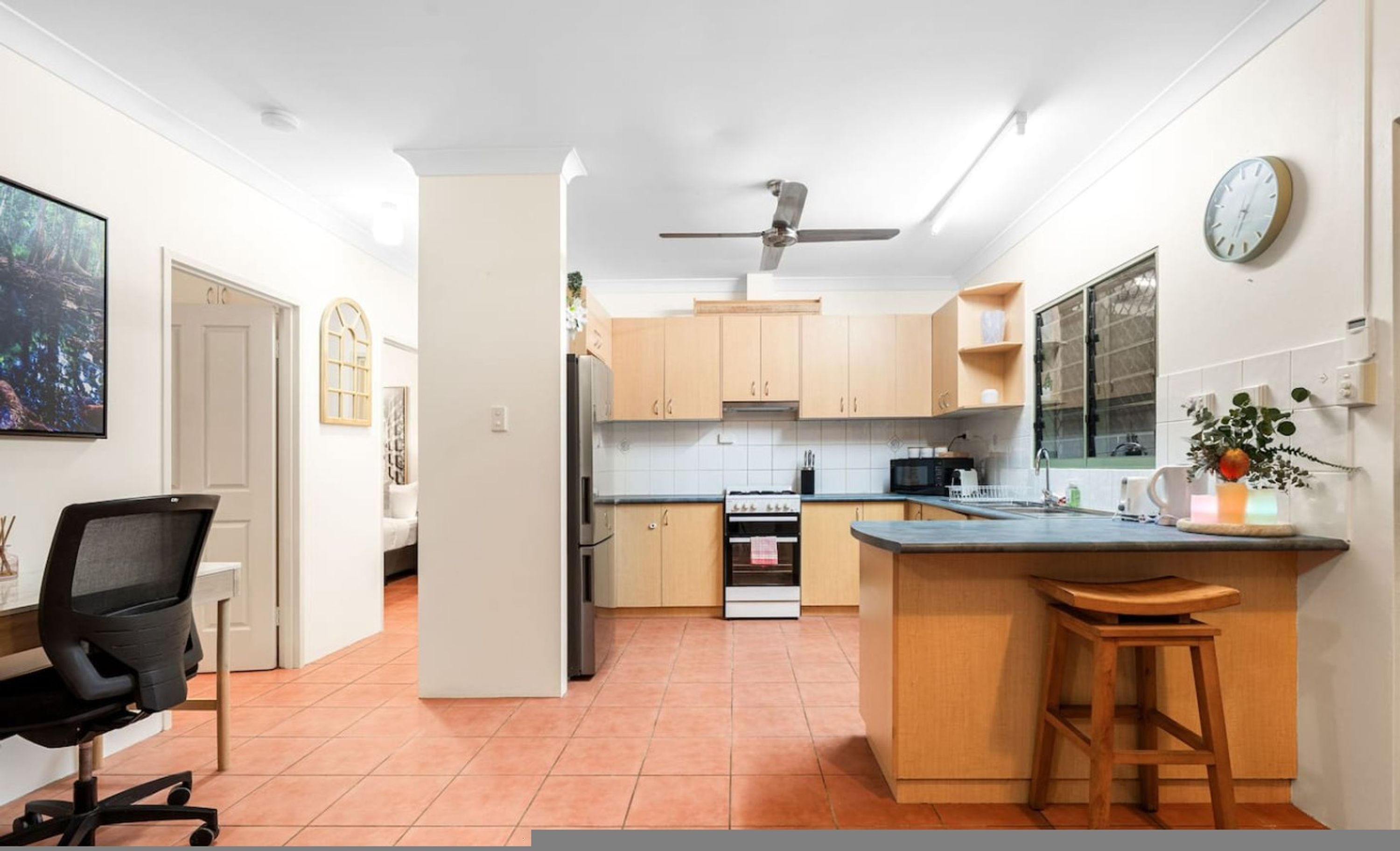 A modern kitchen with wooden cabinets, a built-in oven, a microwave, and a large window.