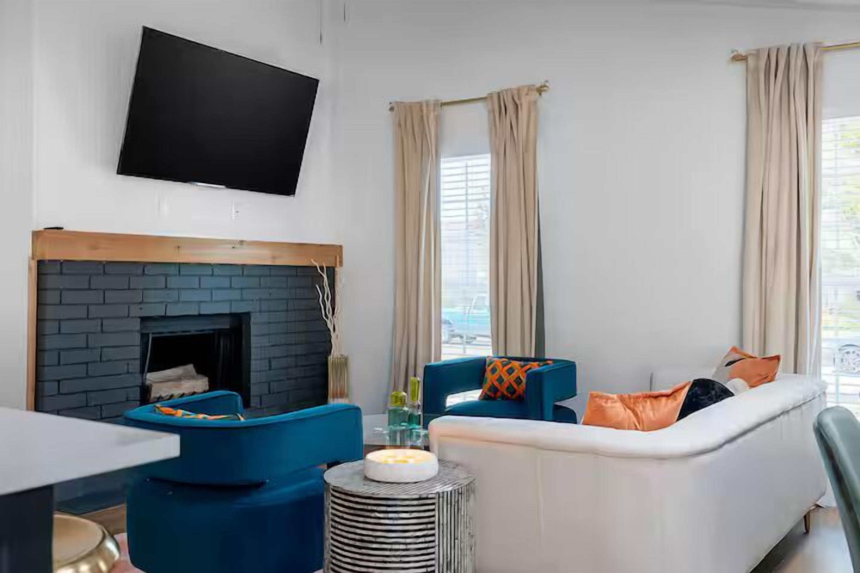 A modern living room with a fireplace, a flat-screen TV, and a sofa with colorful cushions.
