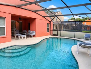 Ein Schwimmbecken mit Liegestühlen und einer überdachten Terrassenbereiches.