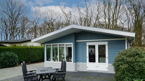 A modern house with a patio, a dining table with chairs, and a garage. - --------deluxe 4 People---------- (Noordwijk)