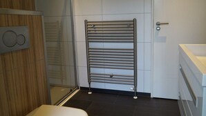 A modern bathroom with a glass shower enclosure, a towel rack, and a white sink. - --------deluxe 4 People---------- (Noordwijk)