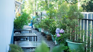 A narrow outdoor pathway with potted plants and tables. - Fix25House Koh Kood (Ko Kood)