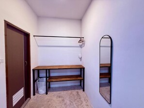 Un pasillo con un banco de madera, un espejo en la pared y una puerta.