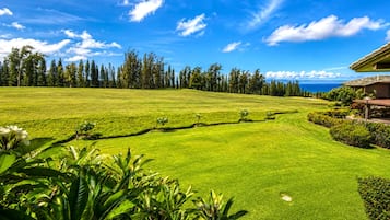 Ein Golfplatz mit gepflegtem Rasen, Bäumen und einem Gebäude mit Satteldach.