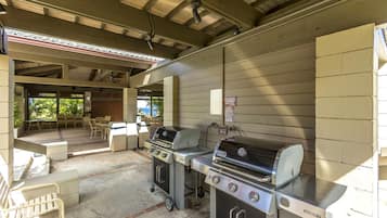 An outdoor barbecue area with two grills, a gas stove, and a sink.