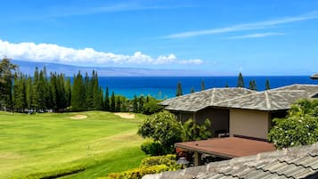 Un campo de golf con vista al océano y un edificio con techo de tejas.