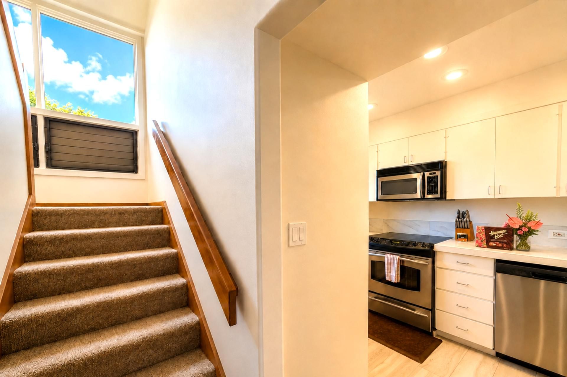A modern kitchen with stainless steel appliances, a built-in oven, and white cabinetry.