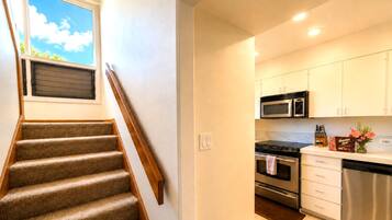 A modern kitchen with stainless steel appliances, a built-in oven, and white cabinetry.