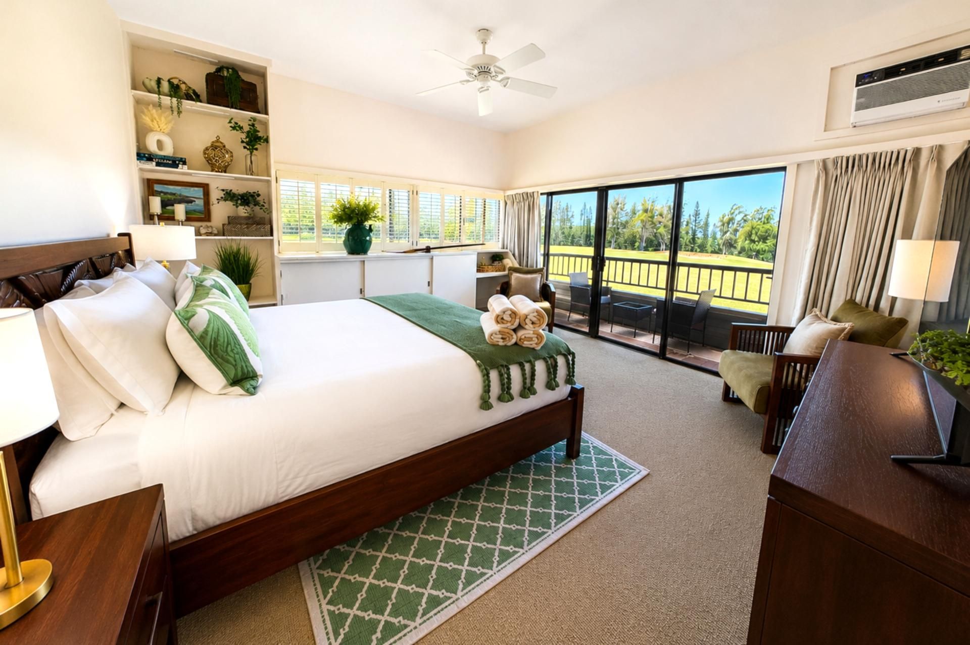 Une chambre d’hôtel avec un grand lit, un balcon avec vue, un ventilateur de plafond et une fenêtre avec des rideaux.