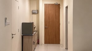 A hotel room with a bed, a desk, a television, a wardrobe, and a door.
